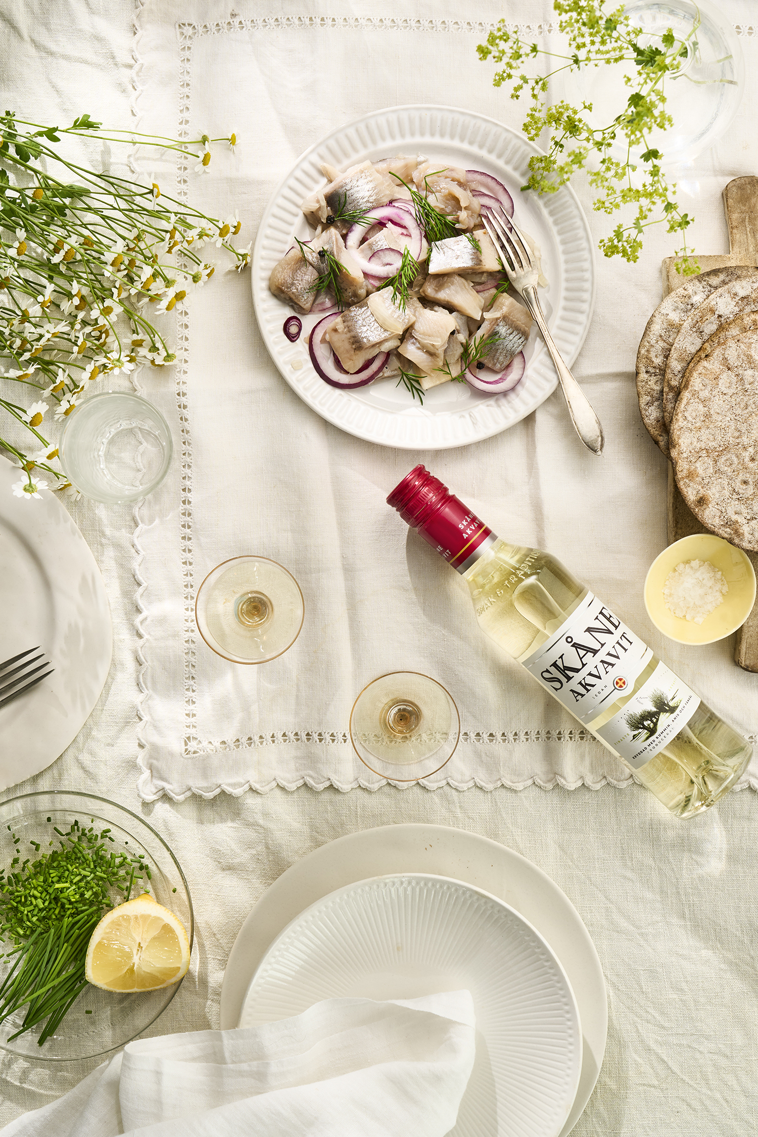 Skåne Akvavit på midsommarbordet med sil, knäckebröd, citron och gräslök
